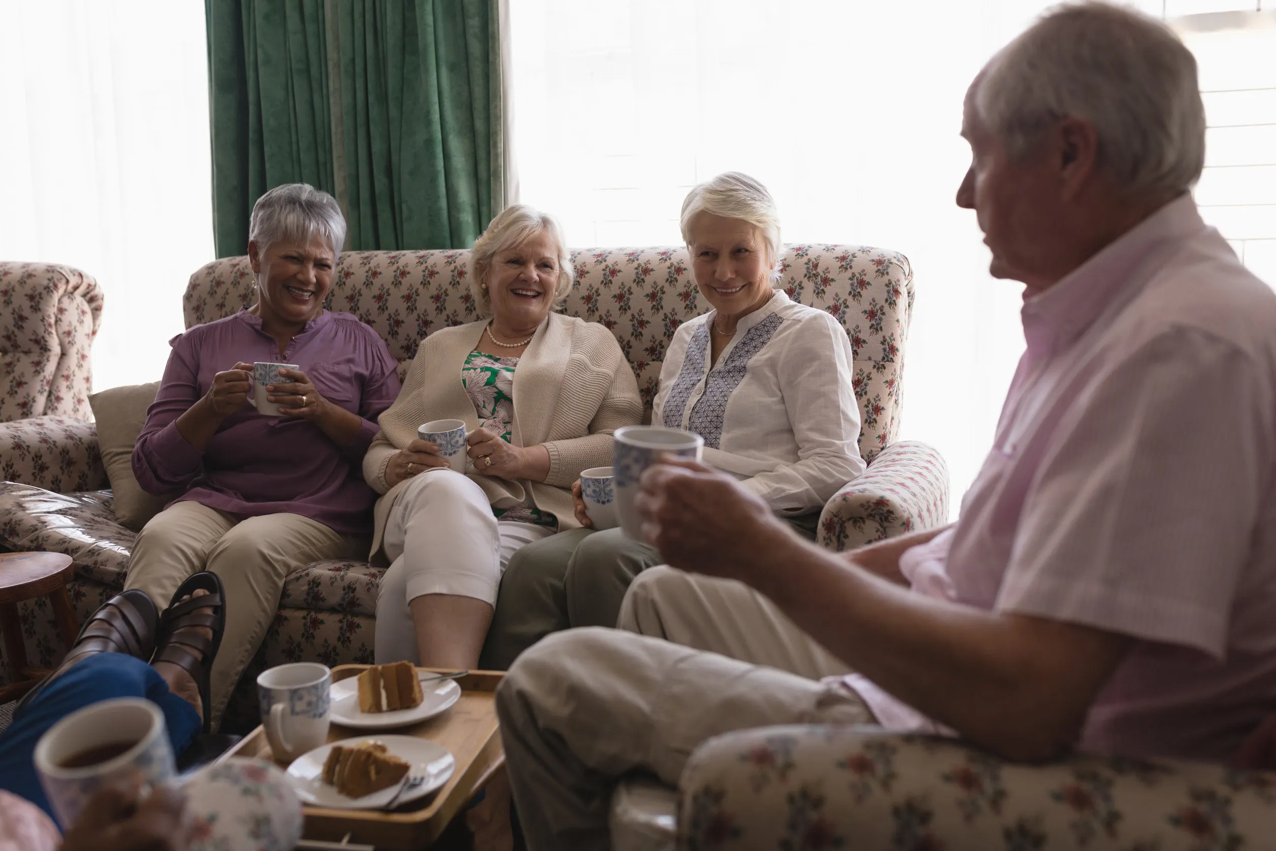 Side view of senior people having coffee and cake in living room at home Side view of senior people having coffee and cake in living room at home